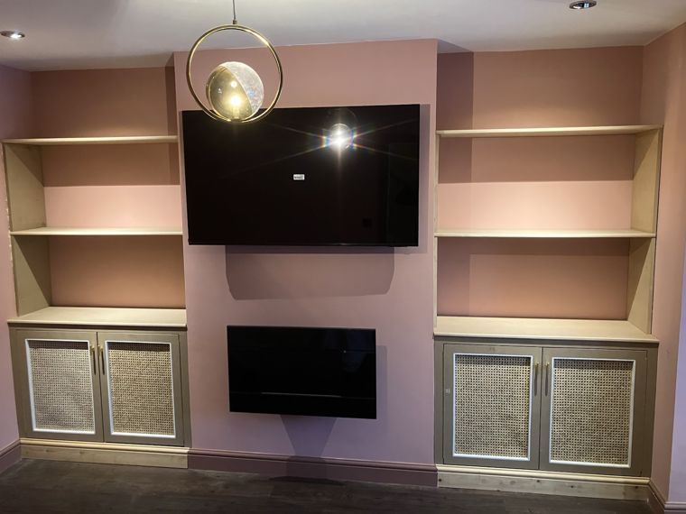 Alcove units either side of a chimney breast, cane-panel doors below open shelves