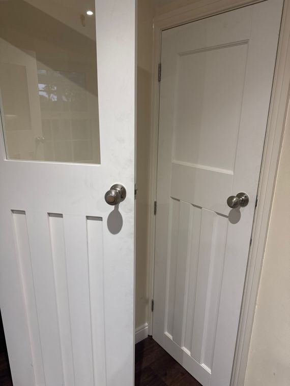 Two white panelled doors, one half-glazed, with round metal knobs