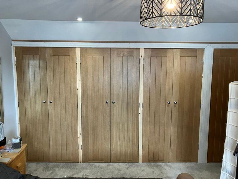Panelled wardrobe doors across a bedroom wall, the frame still unpainted